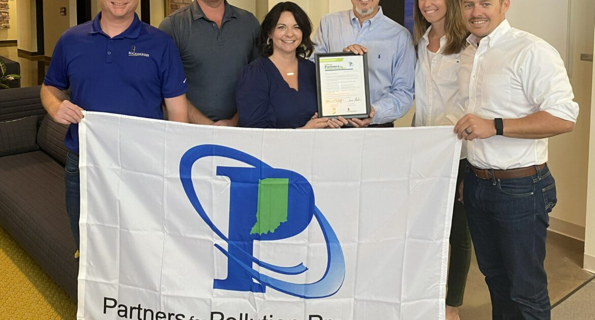 Buckingham employees posing for camera in front of "Partners for Pollution Prevention" flag