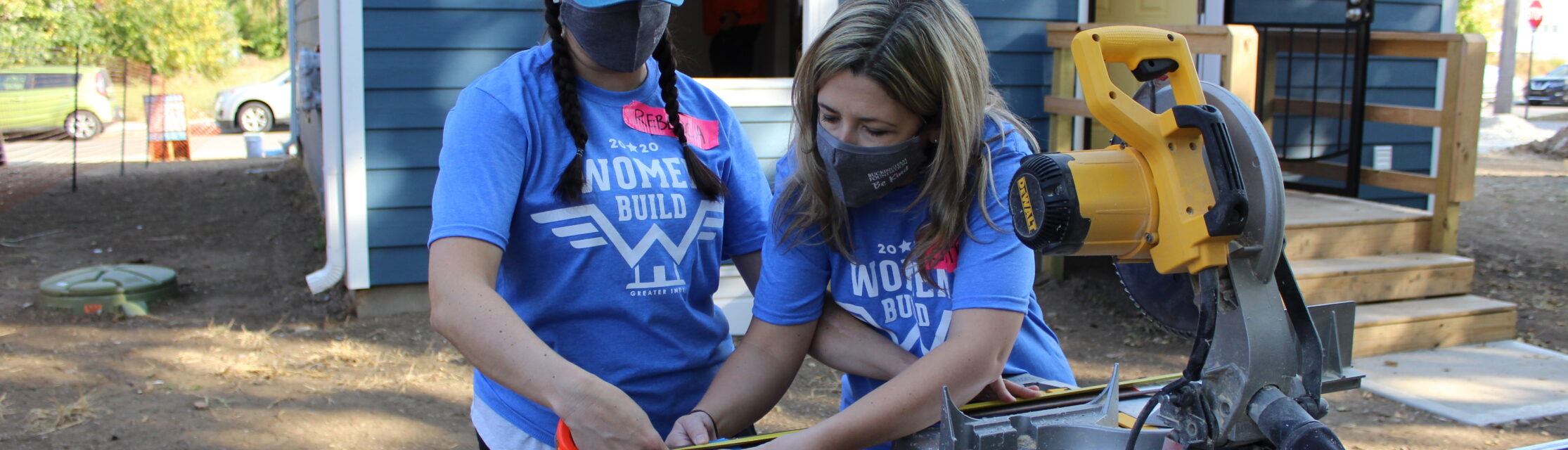 Two women using saw during a volunteer event. 