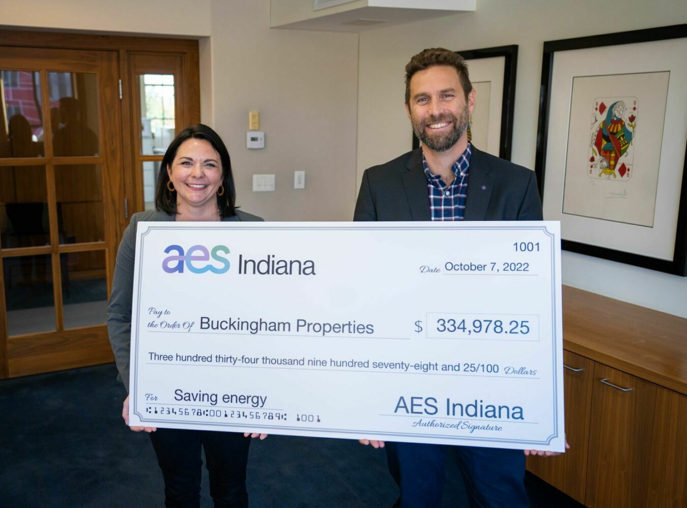 Buckingham's Director of Sustainability posing with check from AES for energy savings. 